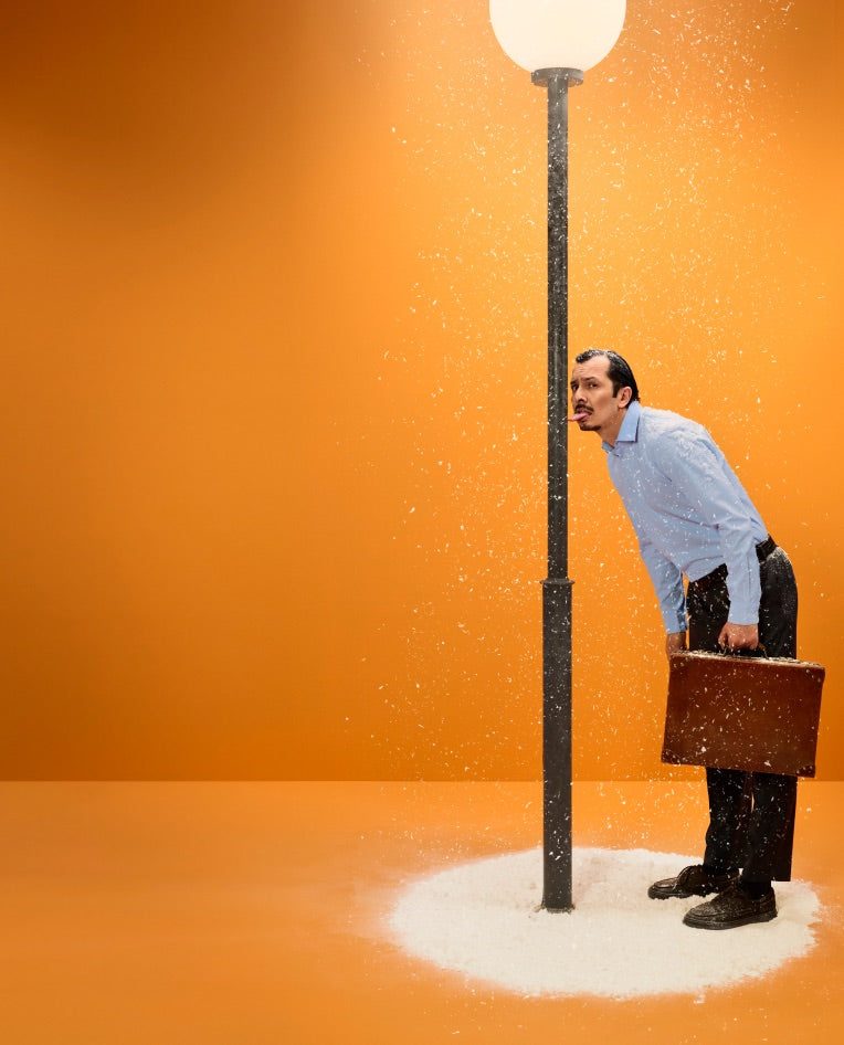 A man in a shirt and tie leaning against a lamppost in a snow drift